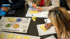 Frauen sitzen an einem Tisch und arbeiten an Matrizen