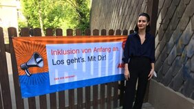 Frau steht vor Plakat zur Inklusionsförderung