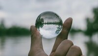 Kleine Glaskugel wird zwischen Daumen und Zeigefinger gehalten