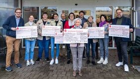 240716 Menschen halten symbolische Schecks hoch