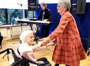 Frau tanzt mit Frau im Rollstuhl