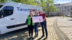 Ricarda und Udo Niedergerke übergeben am Tierarztmobil einen symbolischen Scheck über 10.000 EUR an Katja Seifert