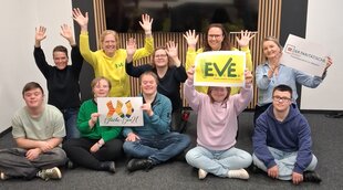 Menschen sitzen mit Plakaten und erhobenen Händen